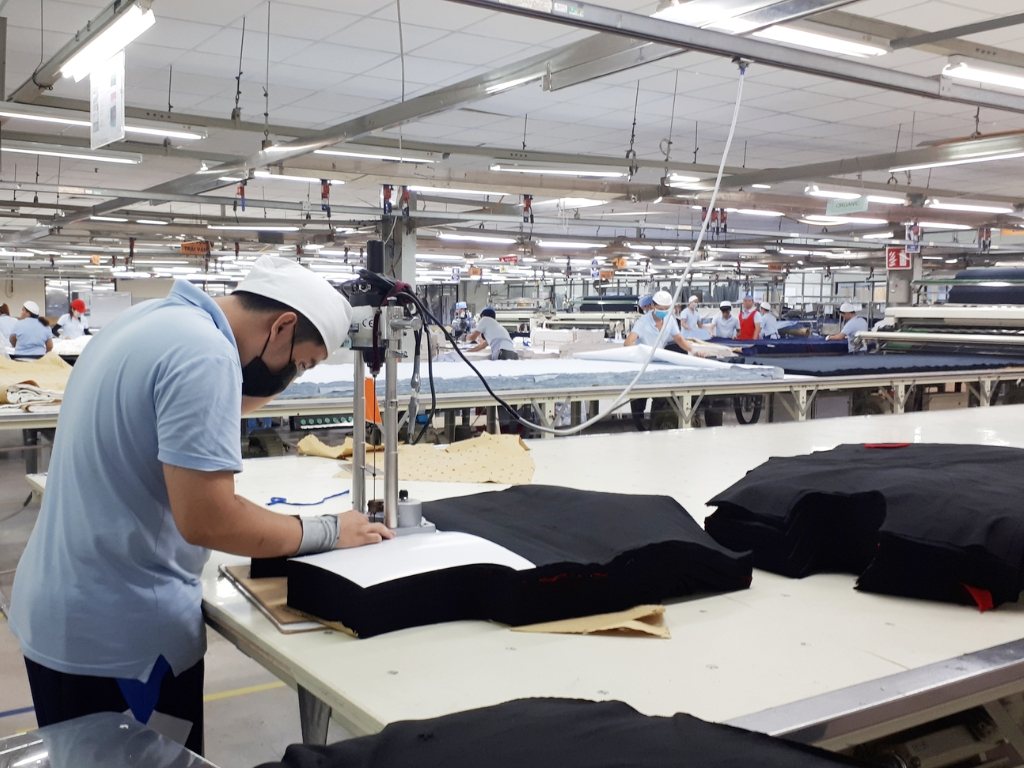 Công nhân sử dụng máy chuyên dụng để cắt vải theo đường vẽ của sơ đồ rập