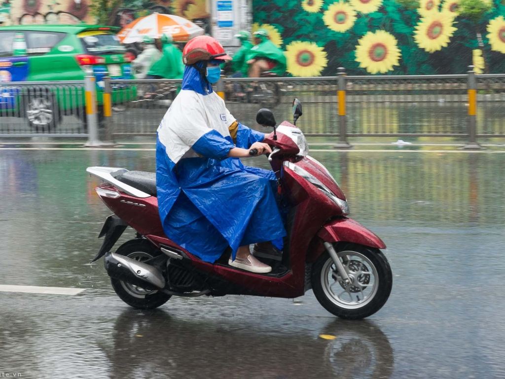 Bạn hãy ngồi đè lên phần vạt sau của áo mưa 1 người mặc để cố định lại