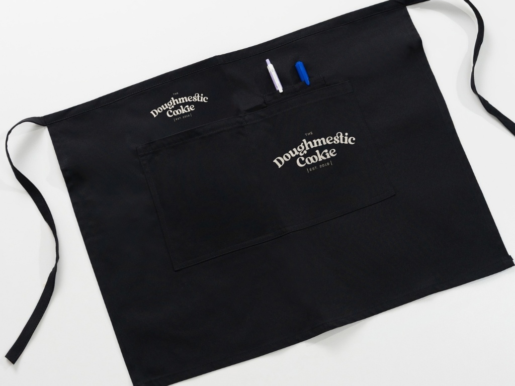 Hình thêu logo màu trắng giúp tạo điểm nhấn trên chiếc tạp dề đen