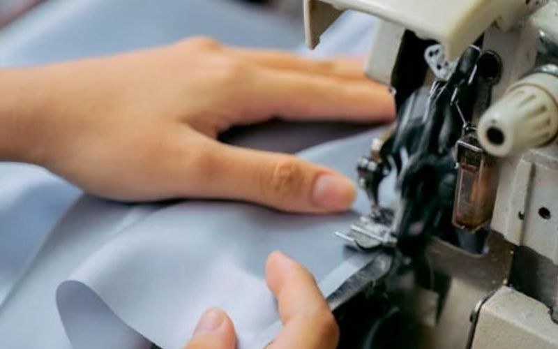 Sử dụng máy may để may cố định khóa kéo vào thân áo