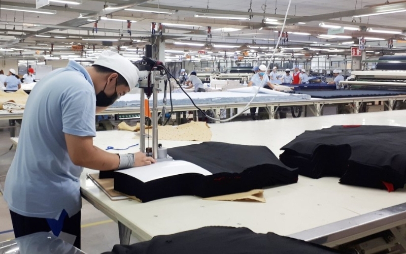 Workers use specialized machines to cut fabric according to pattern layouts